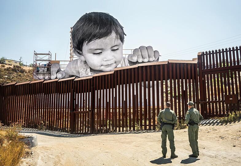 Dem französischen Foto- und Street-Art-Künstler JR fällt immer etwas Aufsehenerregendes ein. Hier lässt er ein gigantisches Baby von der mexikanischen Seite aus über den Grenzzaun in die Verenigten Staaten blicken.