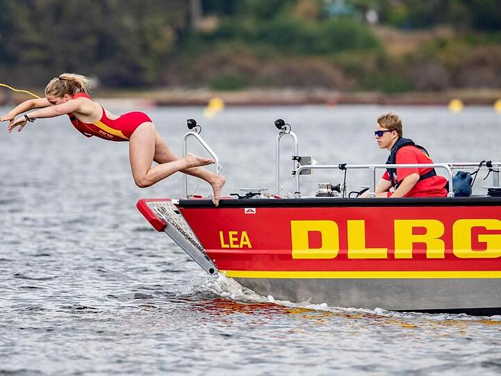 Eine Rettungsschwimmerin der DLRG springt in einen See. Foto: Marcel Kusch/dpa/Symbolbild
