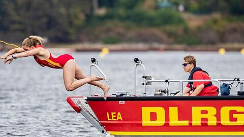 Eine Rettungsschwimmerin der DLRG springt in einen See. Foto: Marcel Kusch/dpa/Symbolbild