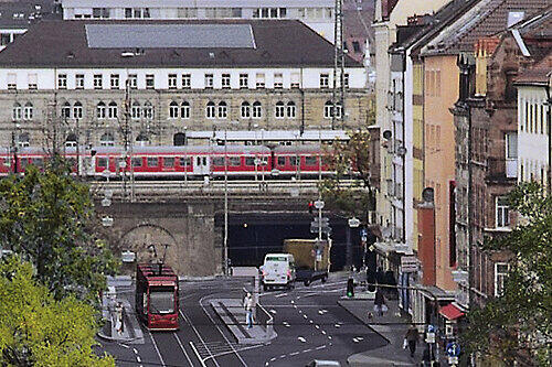 Blick vom Süden in die Pillenreuther Straße, wie sie nach dem Ausbau einmal aussehen wird: Straßenbahn und Autos teilen sich die Fahrbahn. Der Straßenbahnzug (hinten) steht an der künftigen Haltestelle Celtisstraße.