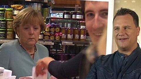 Ex-Dschungelkönig Peer Kusmagk (Mitte) lacht und staunt, als er beim Dreh zu Guido Maria Kretschmers (re.) Show plötzlich mit Angela Merkel (li.) an der Supermarkt-Kasse steht