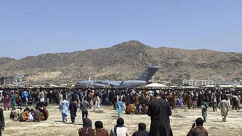 Hunderte Menschen haben sich auf dem Gelände des internationalen Flughafens in Kabul versammelt.