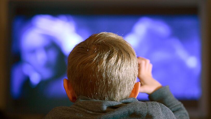 Ein Junge sitzt vor dem Fernseher.