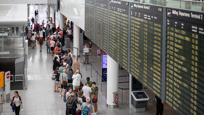 Reisende stehen mit ihrem Gepäck am Flughafen.