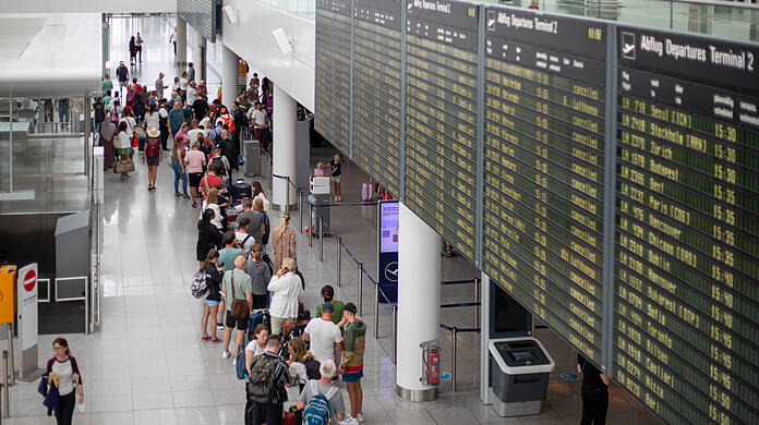 Reisende stehen mit ihrem Gepäck am Flughafen.