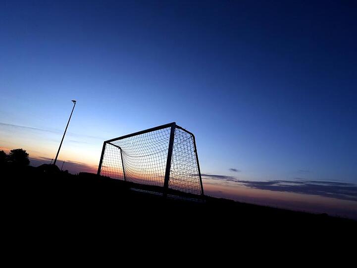Ein Fußballtor hebt sich auf dem Sportplatz zur blauen Stunde vor dem wolkenlosem Himmel ab. Foto: Karl-Josef Hildenbrand/Archivbild