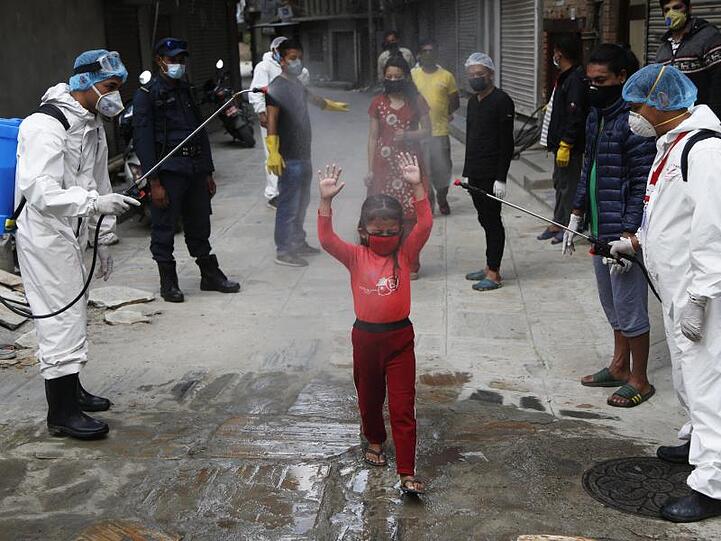 Ein Mädchen in Nepal wird mit Desinfektionsmittel besprüht.