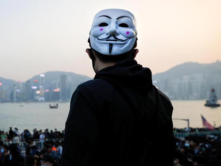 Ein prodemokratischer Demonstrant mit Guy-Fawkes-Maske beobachtet eine Kundgebung in Hongkong.