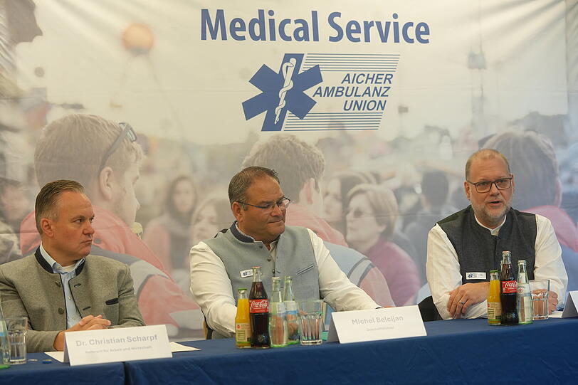 Auf der Pressekonferenz der Aicher Ambulanz wurden die Neuerungen f&uuml;r das Oktoberfest 2026 bekanntgegeben. Auf dem Bild: Wiesn-Chef Christian Scharpf (l.,SPD), Aicher-Gesch&auml;ftsf&uuml;hrer Michel Belcijan (M.) und Chefarzt Dr. Philip Kampmann.