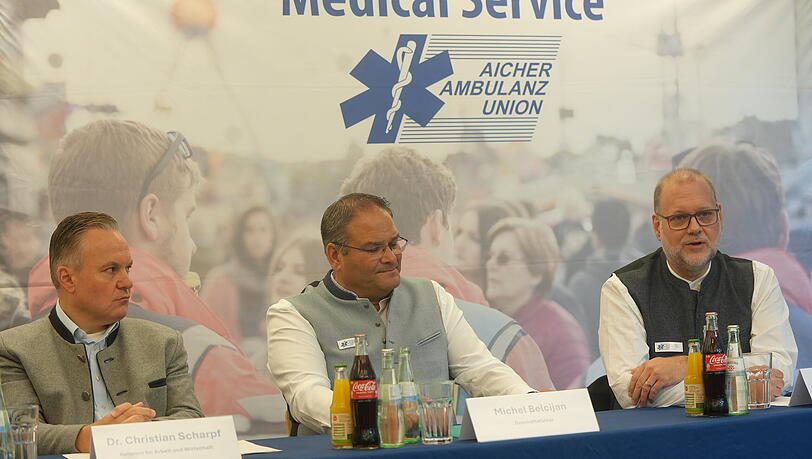 Auf der Pressekonferenz der Aicher Ambulanz wurden die Neuerungen f&uuml;r das Oktoberfest 2026 bekanntgegeben. Auf dem Bild: Wiesn-Chef Christian Scharpf (l.,SPD), Aicher-Gesch&auml;ftsf&uuml;hrer Michel Belcijan (M.) und Chefarzt Dr. Philip Kampmann.