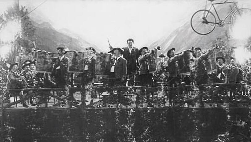 Wirte-Legende Georg "Schorschl" Lang als Dirigent in seinem Wiesn-Zelt 1902 - mit Bergkulisse und Radl, das an der Decke hängt. Wirte-Legende Georg "Schorschl" Lang als Dirigent in seinem Wiesn-Zelt 1902 - mit Bergkulisse und Radl, das an der Decke hängt.