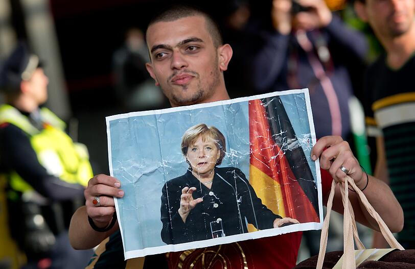 Ankunft mit der Kanzlerin in den Händen: Dieses Foto wurde zum Sinnbild für die Flüchtlingspolitik von Angela Merkel. In der CSU kommt ihr offener Kurs nicht gut an.
