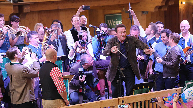 Erst eine kühle Maß, danach Dirigieren auf der Bühne: Die Bilder vom Schwarzenegger-Besuch im Schützen-Festzelt.