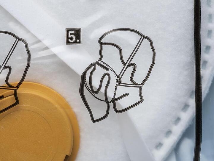 Anleitung für das korrekte Aufsetzen der Maske auf der Verpackung einer FFP3-Atemschutzmaske. Foto: Christian Beutler/KEYSTONE/dpa/Symbolbild