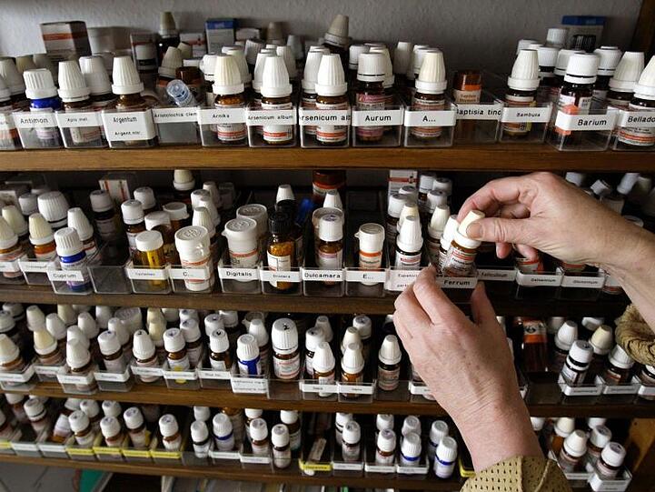 Ein Schrank von Fläschchen mit homöopathischen Mitteln in der Praxis einer Heilpraktikerin. Foto: Frank Rumpenhorst/dpa