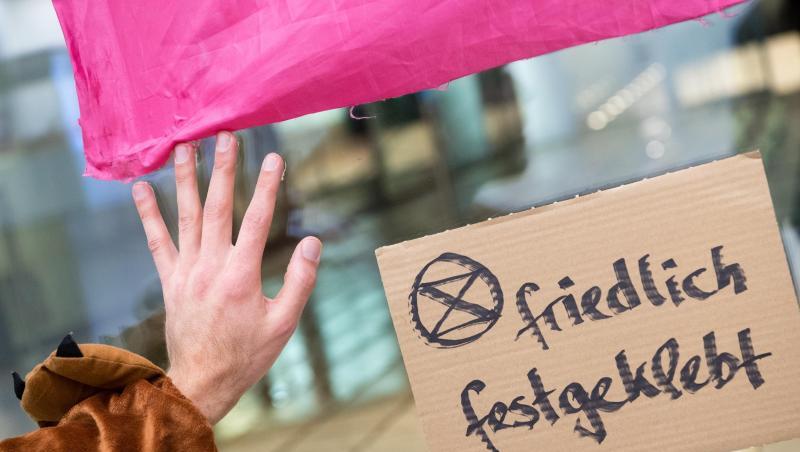 Thomas Nier, Aktivist der Bewegung Extinction-Rebellion klebt mit seiner Hand an einer Scheibe der Siemens-Konzernzentrale. Foto: Matthias Balk/dpa Thomas Nier, Aktivist der Bewegung Extinction-Rebellion klebt mit seiner Hand an einer Scheibe der Siemens-Konzernzentrale. Foto: Matthias Balk/dpa