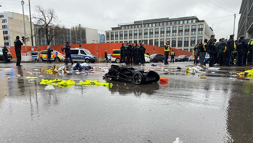 Das Epizentrum des Albtraums am schwarzen Donnerstag in M&uuml;nchen: An der Kreuzung Seidl-/Karlstra&szlig;e liegt kurz nach der Terrorfahrt am 13. Februar 2025 ein Kinderwagen v&ouml;llig demoliert auf der regennassen Stra&szlig;e. Im Vordergrund ein Turnschuh, der wohl einem der Opfer des Anschlags geh&ouml;rt.