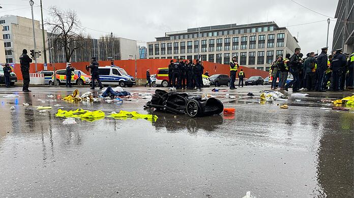 Das Epizentrum des Albtraums am schwarzen Donnerstag in M&uuml;nchen: An der Kreuzung Seidl-/Karlstra&szlig;e liegt kurz nach der Terrorfahrt am 13. Februar 2025 ein Kinderwagen v&ouml;llig demoliert auf der regennassen Stra&szlig;e. Im Vordergrund ein Turnschuh, der wohl einem der Opfer des Anschlags geh&ouml;rt.