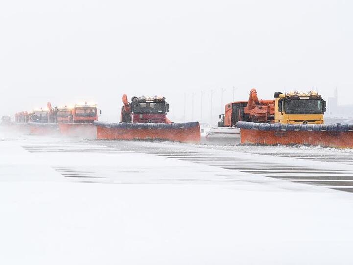 Räumfahrzeuge befreien das Rollfeld am Flughafen München von Schnee.