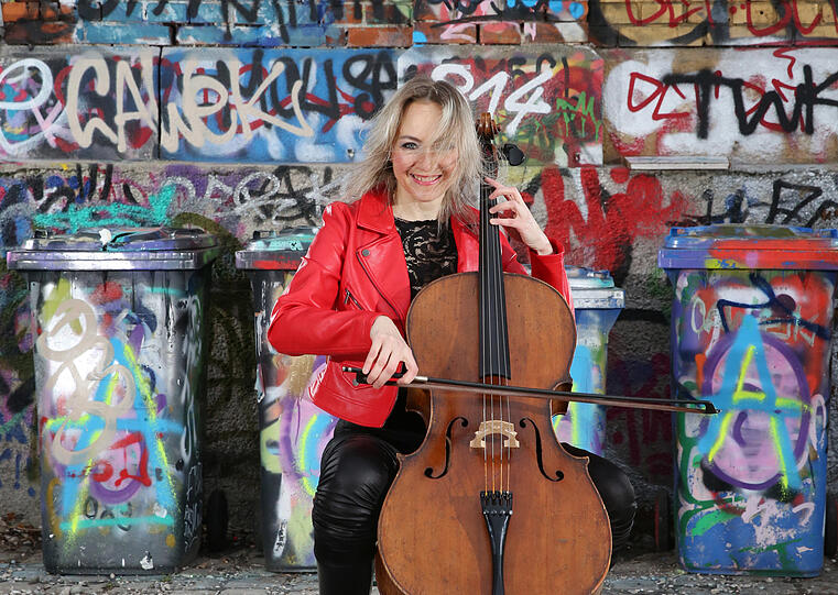 Graffiti und Cello? Passt! Cellistin Anna Rehker mit ihrem Instrument vor kunterbunten Wänden.