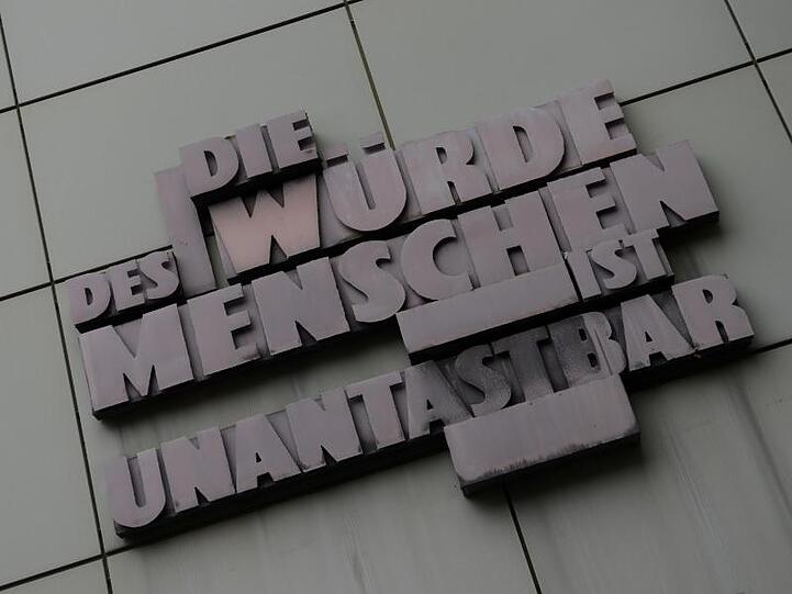 Das Zitat bezüglich der Unantastbarkeit der Würde des Menschen hängt an einer Fassade. Foto: Arne Dedert/dpa/Archivbild