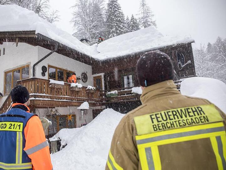 Feuerwehrmänner schaufeln Schnee vom Dach eines Hauses. Foto: Bernd März