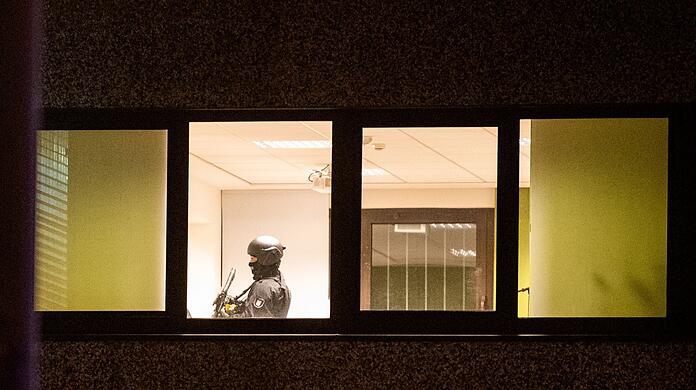 Ein Polizist steht mit einer Waffe in einem Geb&auml;ude.