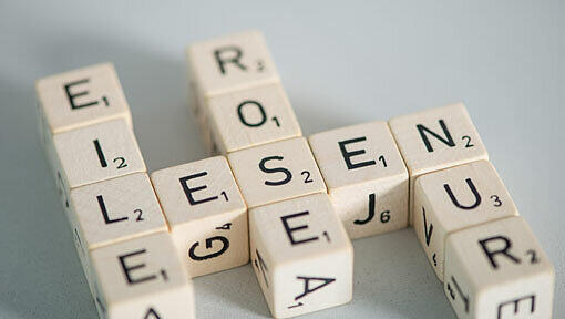 Mit Buchstaben bedruckte Holzwürfel liegen in der Abendakademie. Mit Buchstaben bedruckte Holzwürfel liegen in der Abendakademie.