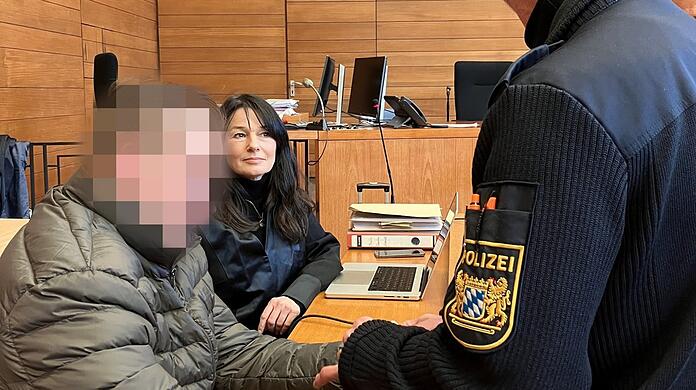 Mit Handschellen und Fußfesseln wird der Angeklagte in den Saal im Landgericht geführt. Neben ihm sitzt seine Wahlverteidigerin Regina Rick.