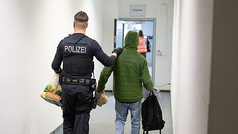 Ein Polizeibeamter bringt einen Mann zu einem Abschiebeflug nach Pakistan. (Archivfoto)
