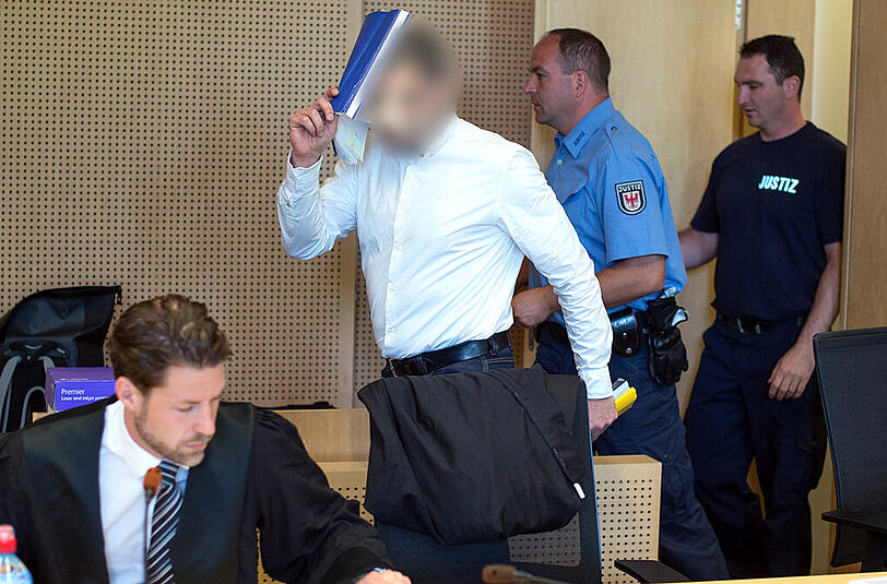 Der Angeklagte Mario K. verdeckt mit einem Hefter sein Gesicht neben seinem Anwalt Christian Lödden (l) vor Beginn eines Verhandlungstages.