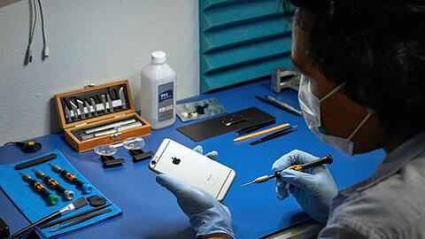 Ein Service-Techniker arbeitet an einem iPhone.