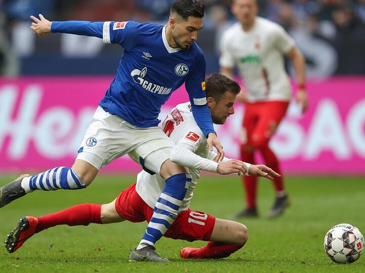 Schalkes Suat Serdar (l) liefert sich mit Augsburgs Daniel Baier einen harten Zweikampf.