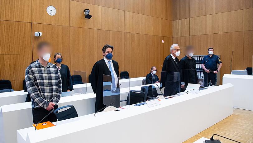 Die zwei wegen Mordes angeklagten Männer (l und 2.v.r.) mit ihren Anwälten vor Beginn der Verhandlung im Sitzungssaal.