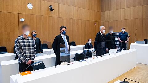 Die zwei wegen Mordes angeklagten Männer (l und 2.v.r.) mit ihren Anwälten vor Beginn der Verhandlung im Sitzungssaal.