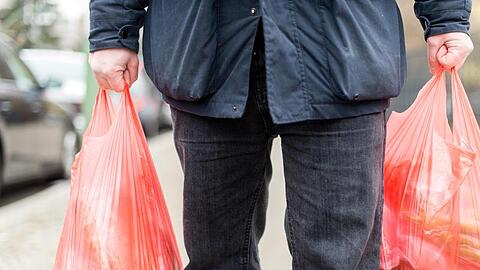 Ein Mann trägt seine Einkäufe in Plastiktüten nach Hause. Foto: Sebastian Gollnow/Archiv