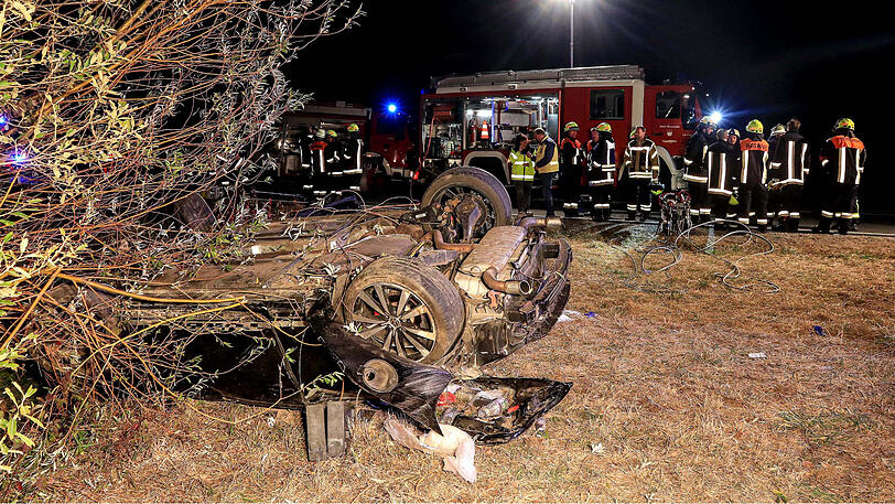 Einsatzkräfte der Feuerwehr stehen in der Nähe des überschlagenen Autos.