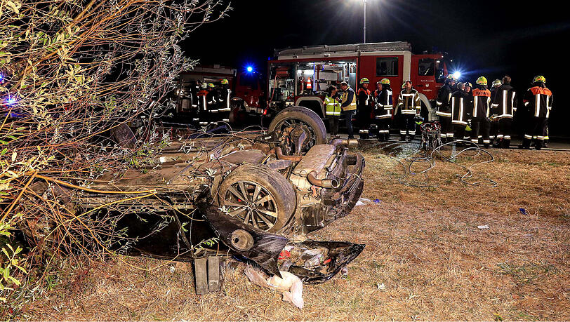 Einsatzkräfte der Feuerwehr stehen in der Nähe des überschlagenen Autos. Einsatzkräfte der Feuerwehr stehen in der Nähe des überschlagenen Autos.
