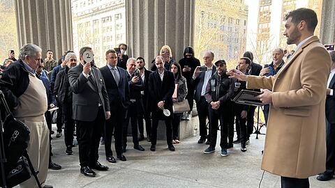 Jacob Garlick (2.v.l), der Bieter mit der Nummer zwei, bietet auf das Flatiron Building in New York.