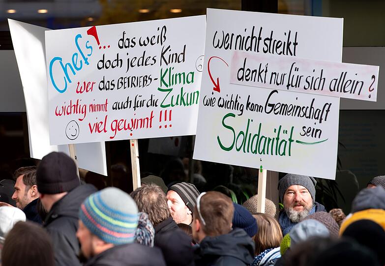 Beim 48-Stunden-Warnstreik halten die Teilnehmer Plakate mit der Aufschrift "Wer nicht streikt denkt nur für sich allein? Wie wichtig kann Gemeinschaft sein - Solidarität" in die Höhe.