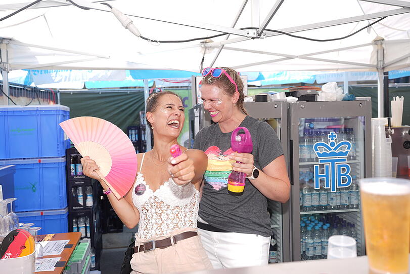 Mit Wasserpistole, F&auml;cher und k&uuml;hlen Getr&auml;nken trotzen zwei Besucherinnen der Sommerhitze beim CSD.