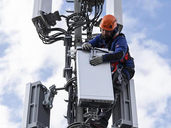 Ein Techniker installiert eine Antenne für das 5G-Funknetz auf einem Hausdach.