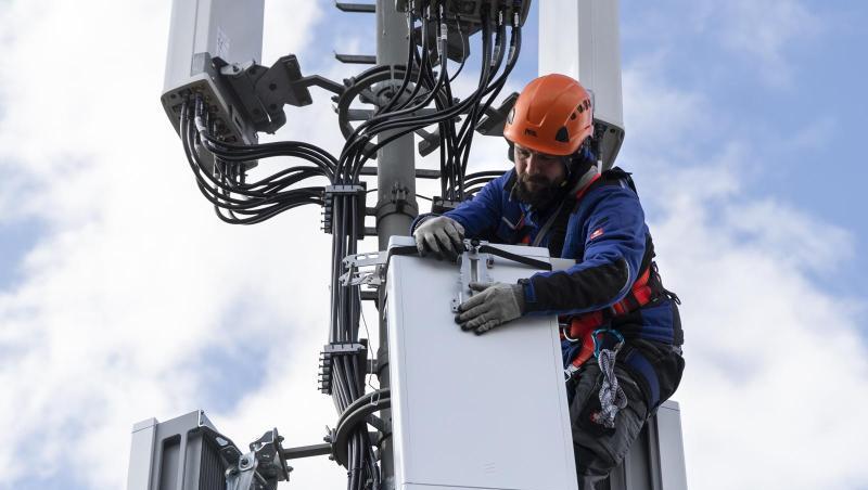 Ein Techniker installiert eine Antenne für das 5G-Funknetz auf einem Hausdach. Ein Techniker installiert eine Antenne für das 5G-Funknetz auf einem Hausdach.