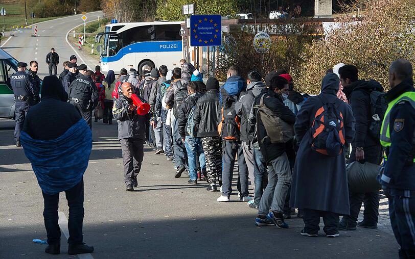 Flüchtlinge warten hinter einer Absperrung auf ihren Grenzübertritt nach Deutschland.
