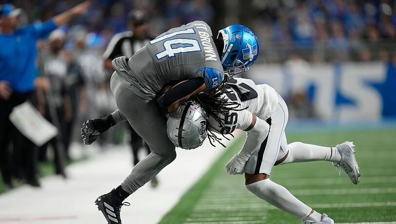 Detroit Lions Wide Receiver Amon-Ra St. Brown (14) wird von Las Vegas Raiders Safety Tre'von Moehrig (25) aus dem Spielfeld gedrängt.