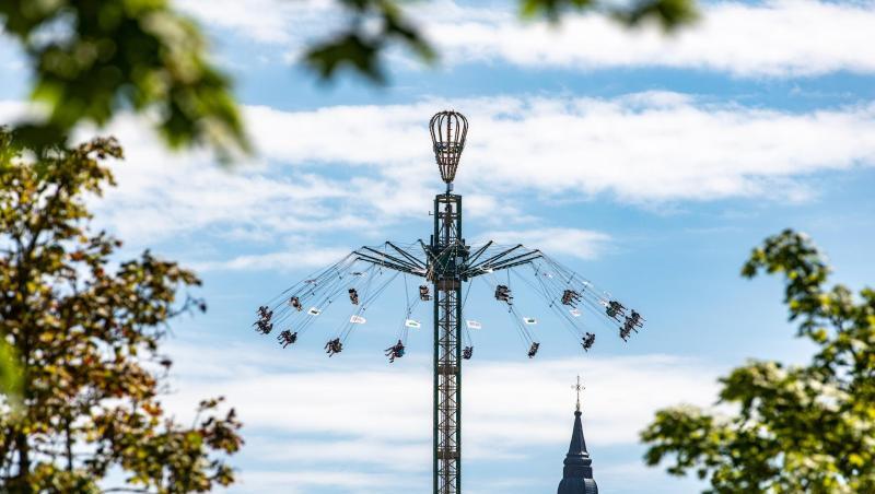 Mit einem Karussell fahren Besucher des Gäubodenvolksfestes vor dem Turm der Basilika St. Jakob. Foto: Armin Weigel Mit einem Karussell fahren Besucher des Gäubodenvolksfestes vor dem Turm der Basilika St. Jakob. Foto: Armin Weigel