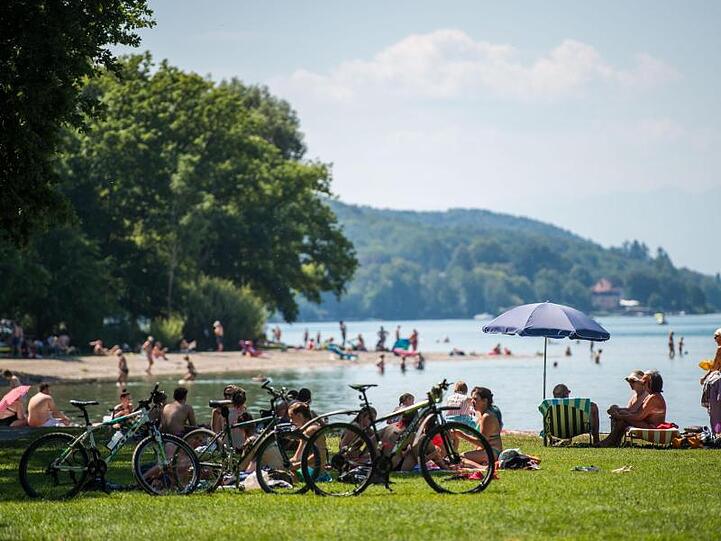 Badegäste liegen am Starnberger See an einem Strand. Foto: Lino Mirgeler/Archivbild