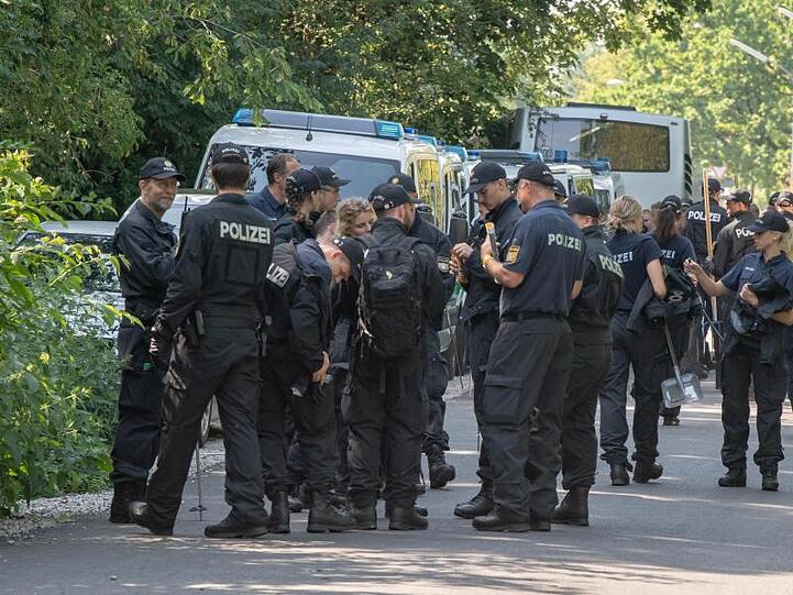 Polizisten sammeln sich auf einer Straße, um anschließend weiter in einem Forst bei München nach zwei Leichen zu suchen. Foto: Peter Kneffel