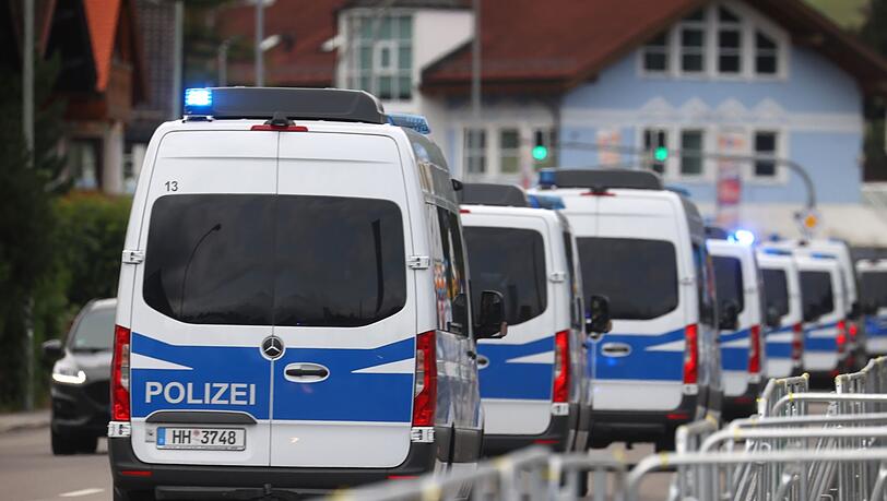 Einsatzfahrzeuge der Polizei fahren hinter Absperrungen.