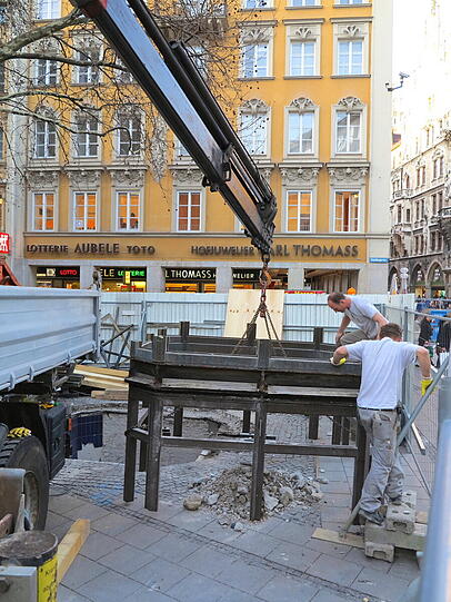 Mit dem Kran heben die Bauarbeiter den alten Aufzug zwischen Sperrengeschoss und Oberfläche am Marienplatz aus den Fugen.